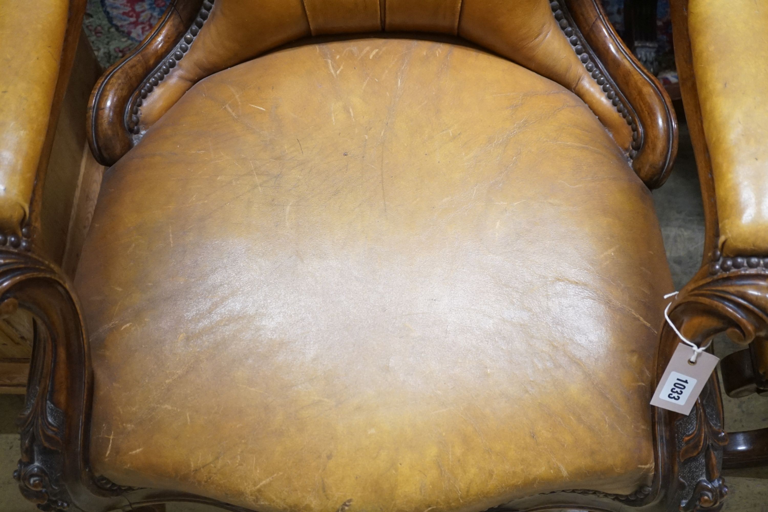 A Victorian carved walnut spoonback open armchair, upholstered in buttoned brown leather, width 69cm depth 66cm height 99cm